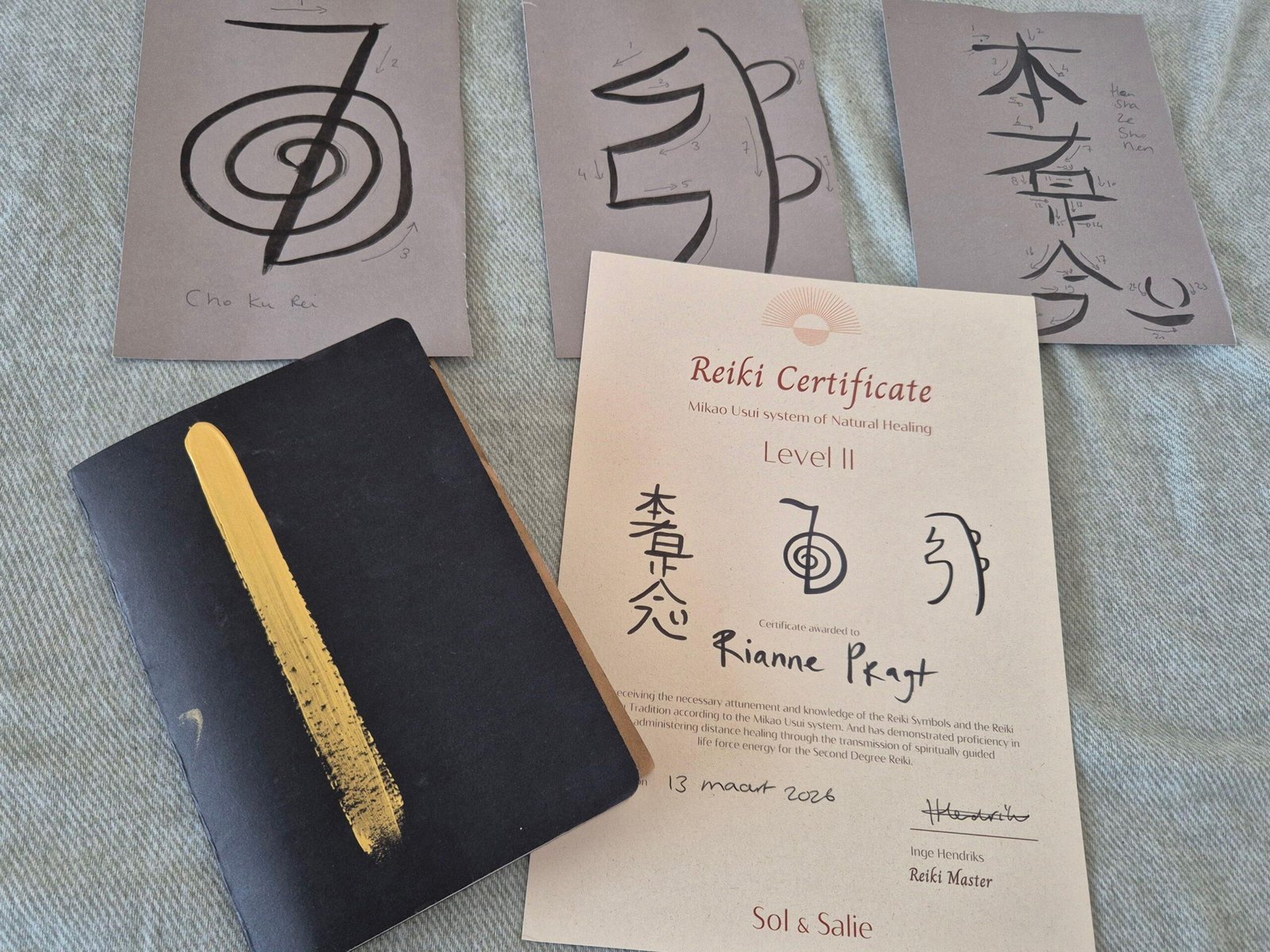 20260318_151434 Certificaat van Reiki 2, de bijbehorende symbolen en een schrift om ervaringen in op te schrijven.